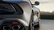 Close-up of the rear side of a silver sports car showing the taillight, dual exhaust pipes, and rear wheel with a side mirror visible.