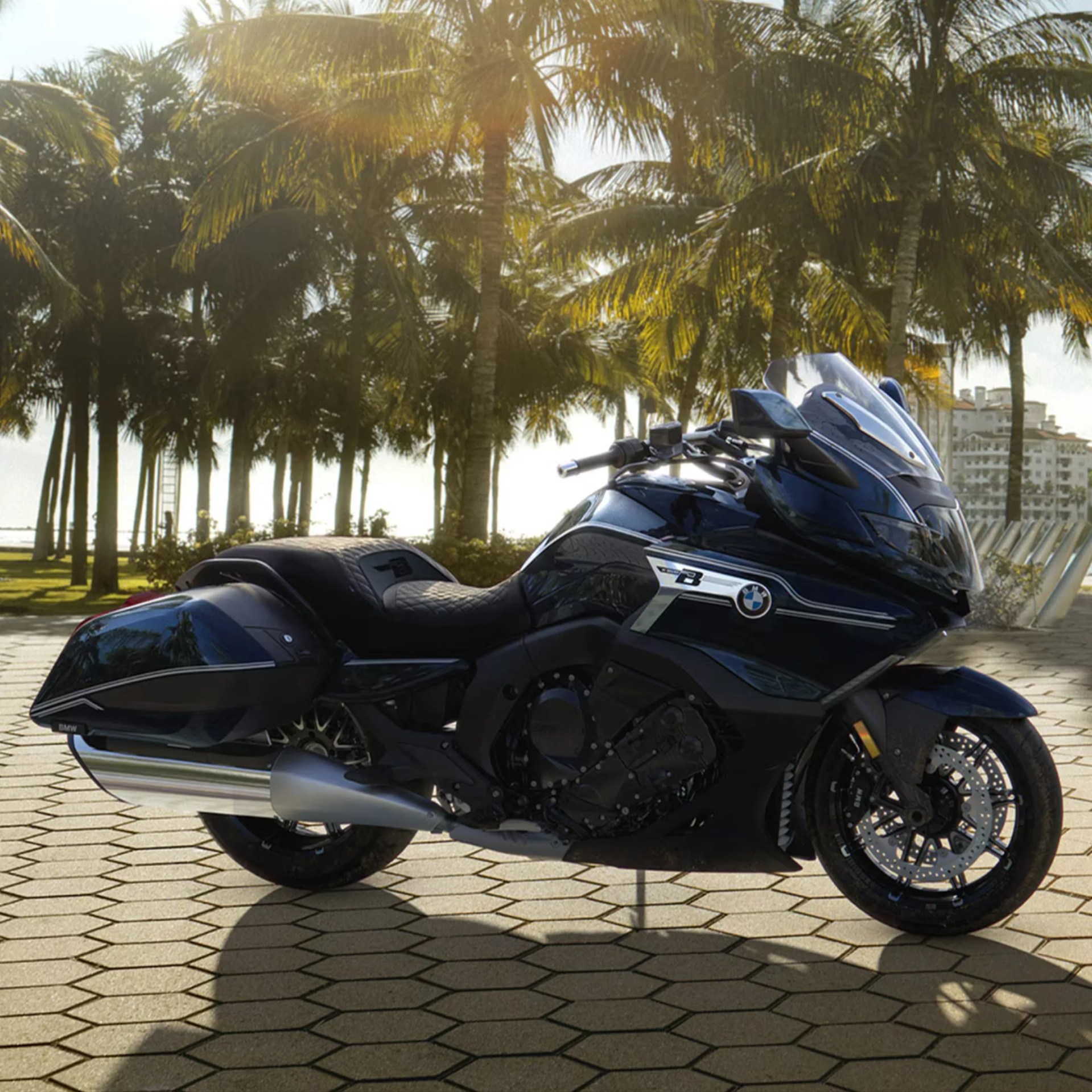 Black BMW touring motorcycle parked on a paved area with palm trees in the background.