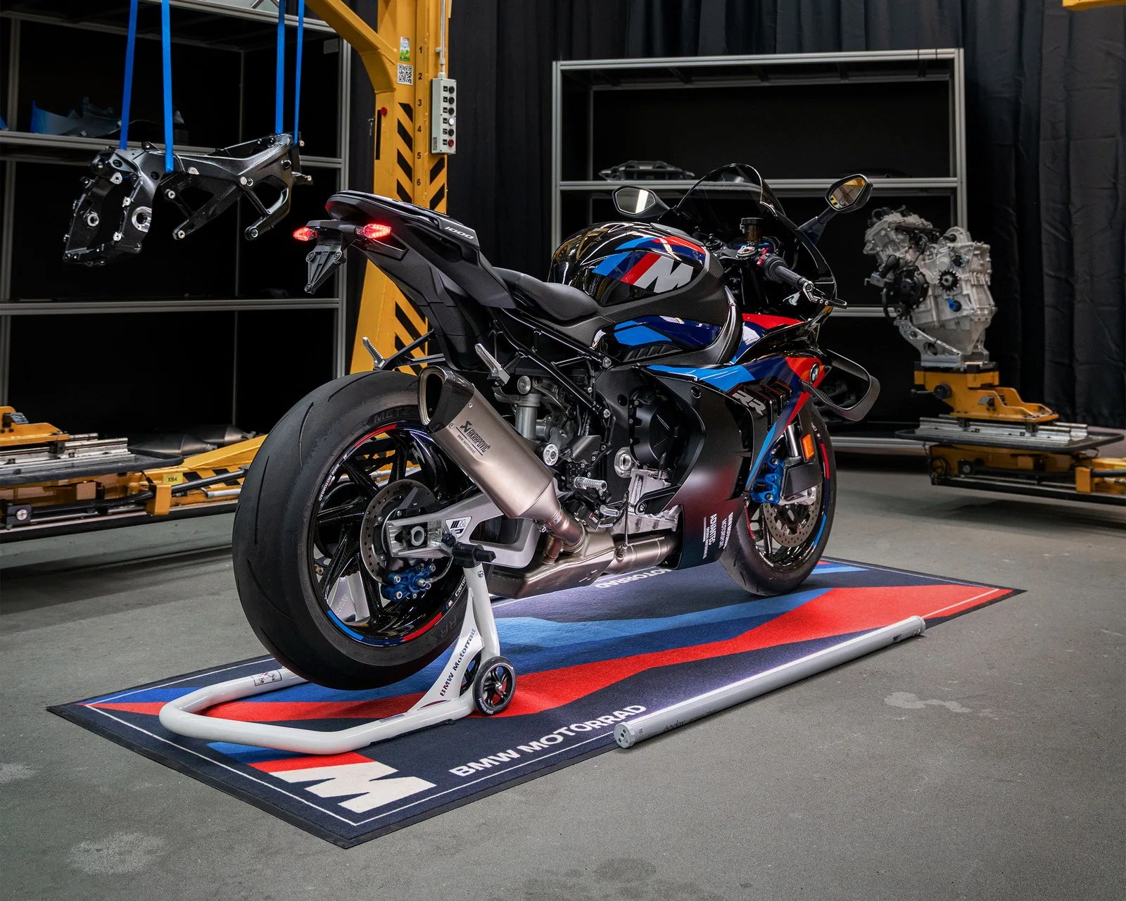 Black BMW sport motorcycle with blue and red accents on a BMW Motorrad mat in a workshop.