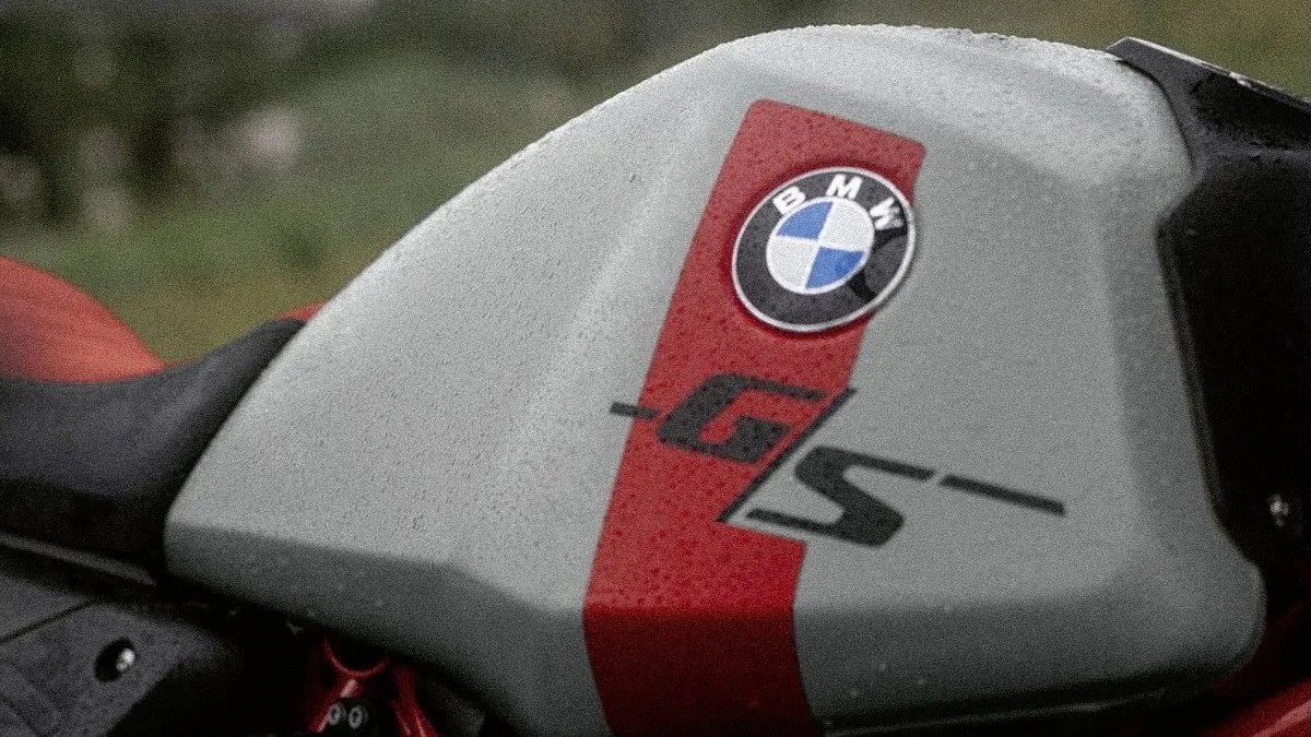 Close-up of a gray motorcycle fuel tank with a red stripe, BMW logo, and "GS" lettering.