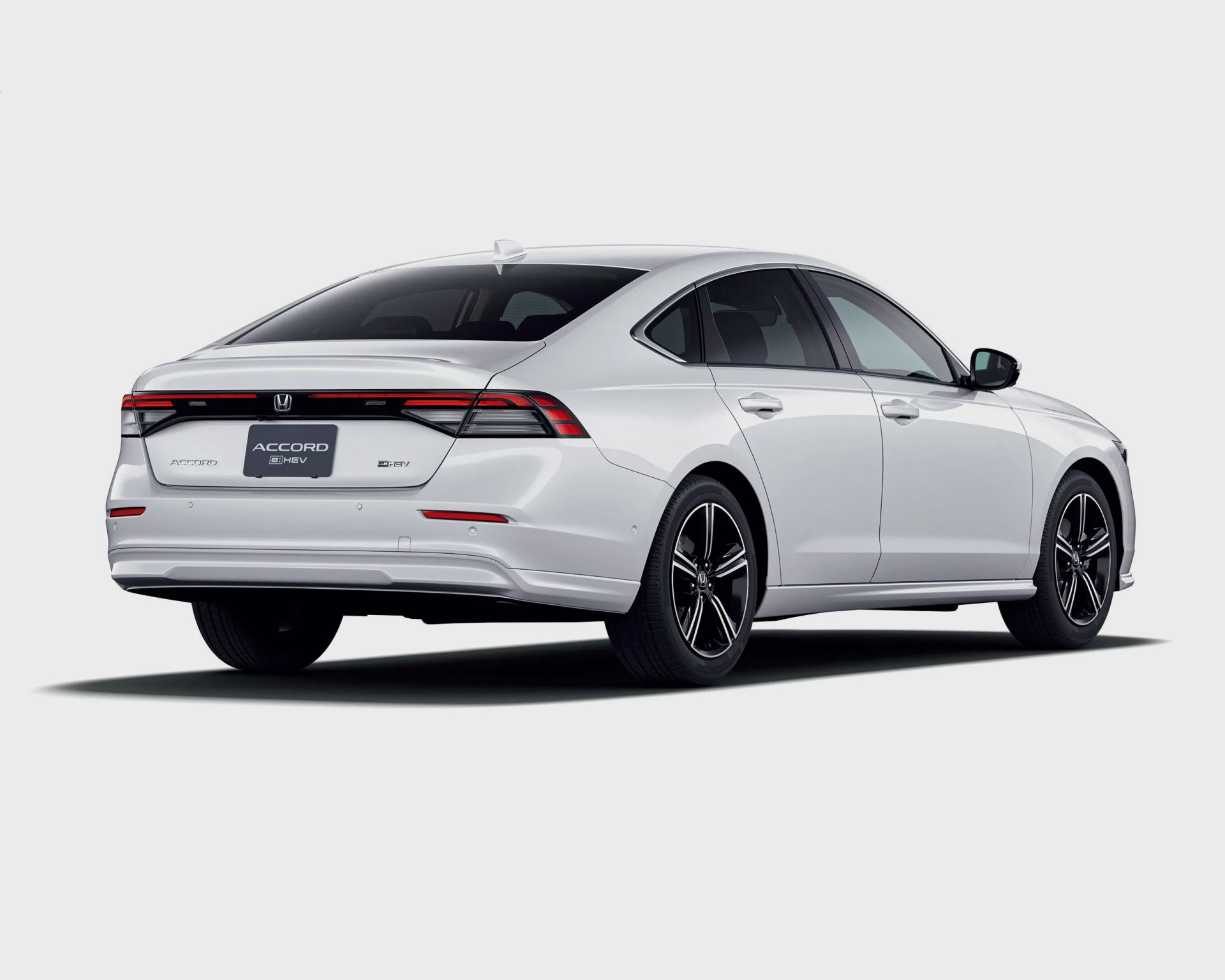 White Honda Accord e:HEV hybrid sedan rear view with black alloy wheels on a white background.
