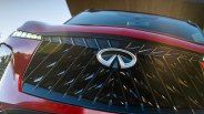 Close-up of a red car front grille with a black geometric pattern and an Infiniti logo in the center.