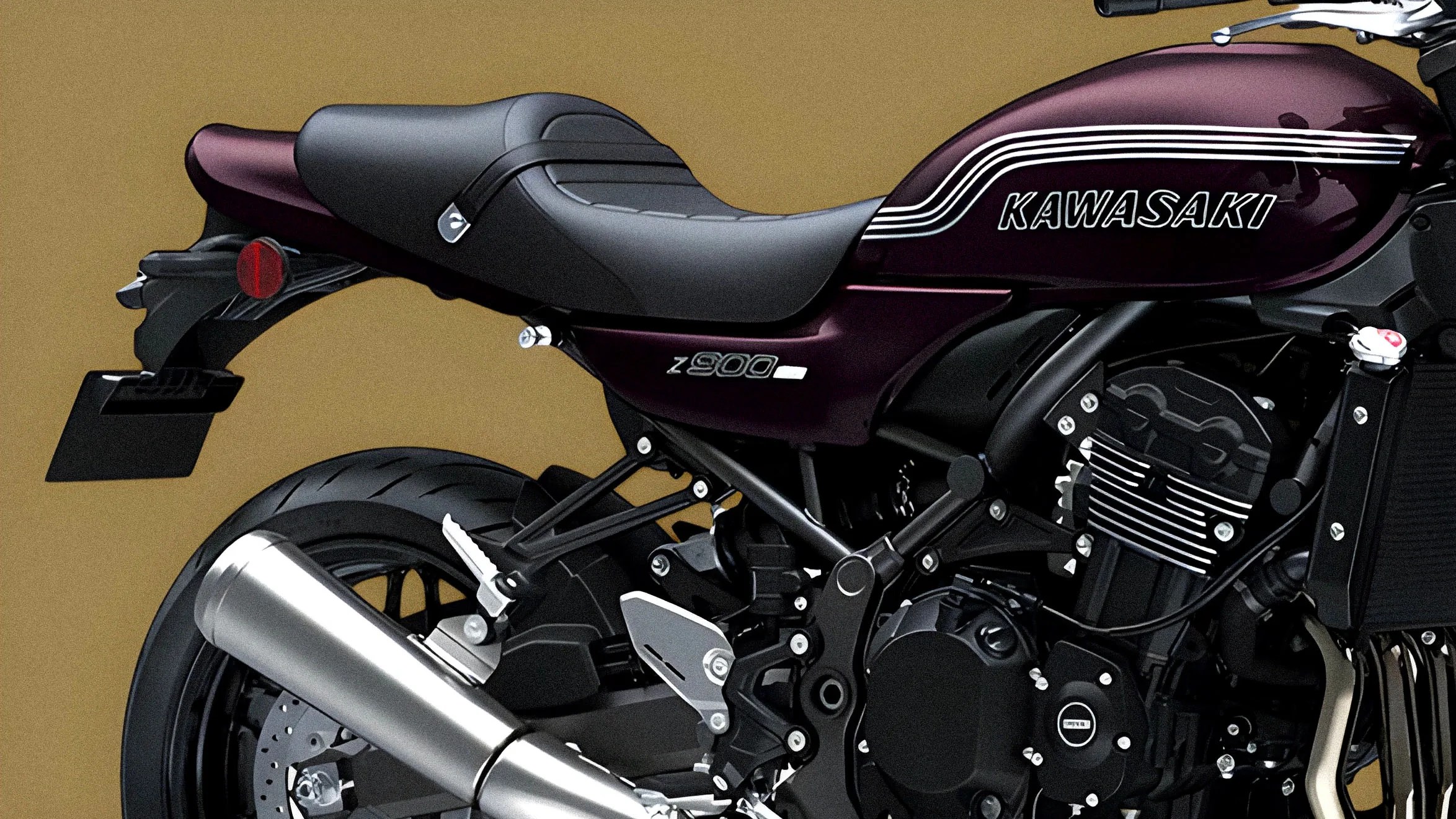 Close-up of a maroon Kawasaki Z900 motorcycle's seat, exhaust pipe, and engine components.