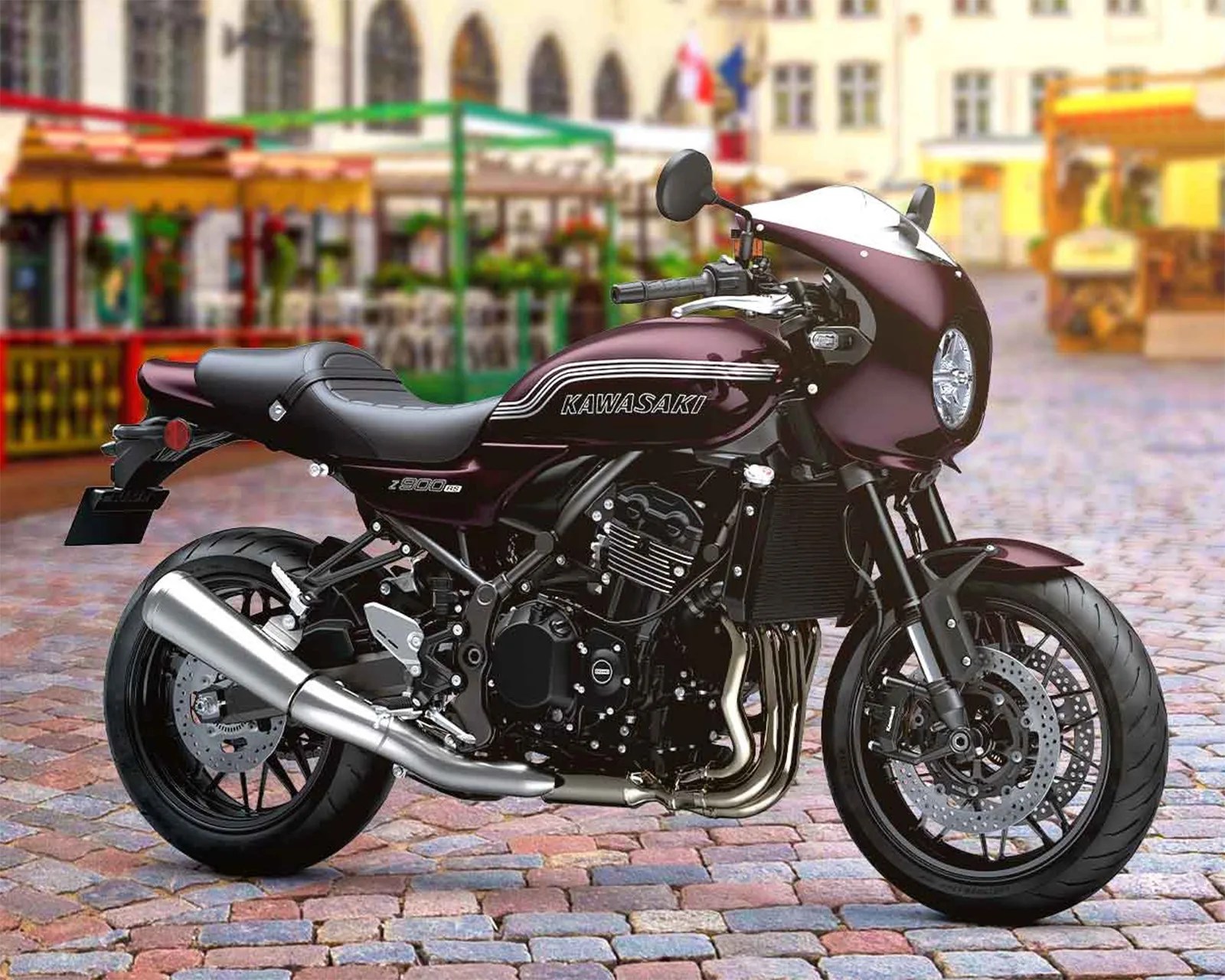 Maroon Kawasaki Z900RS motorcycle with black seat and silver exhaust parked on cobblestone street.