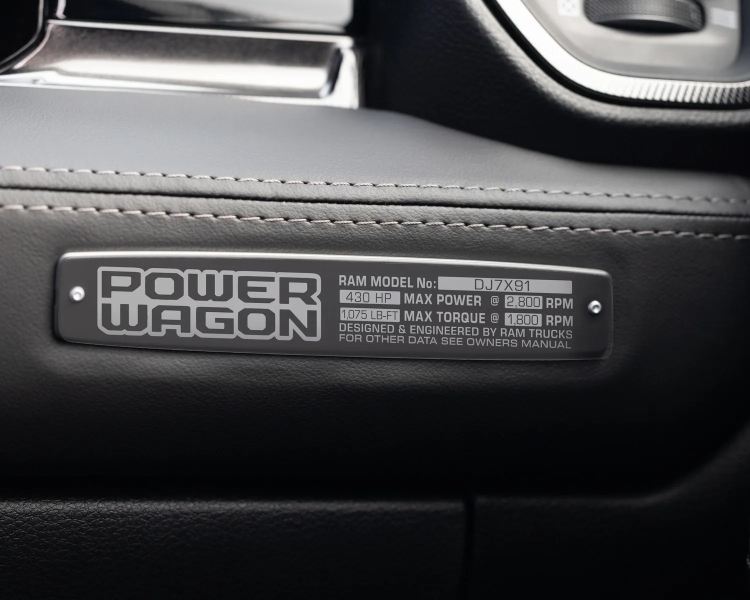 Black metal badge with "POWER WAGON" and engine specs mounted on black stitched leather interior.