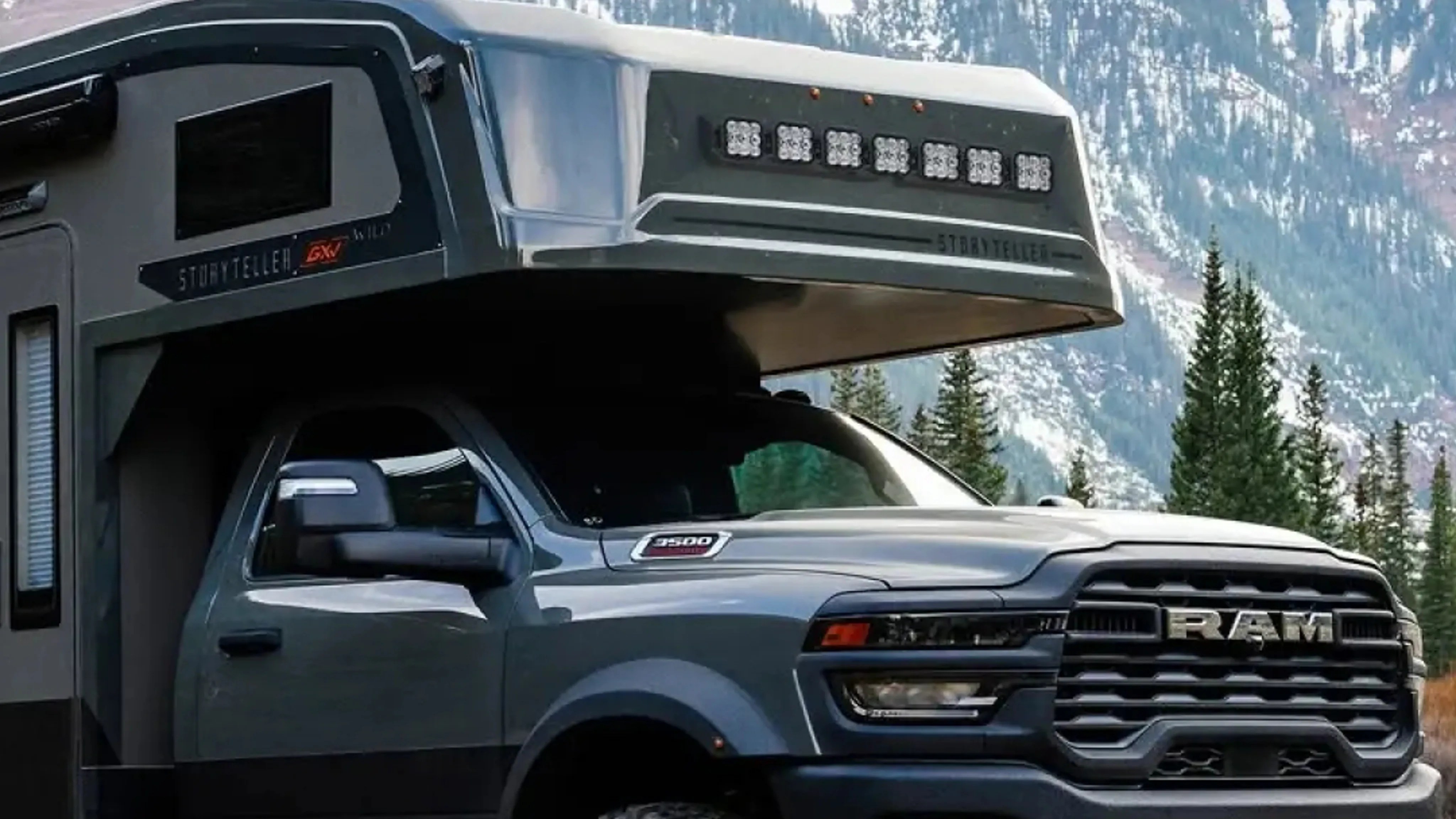 Gray RAM 3500 truck with a Storyteller GX camper attached, set against a mountainous forest background.