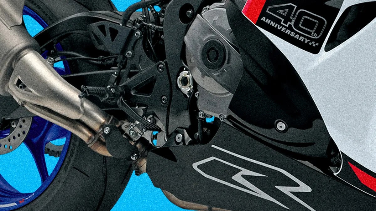 Close-up of a motorcycle's rear wheel, exhaust pipe, and black fairing with "40th Anniversary" and "R" decals.