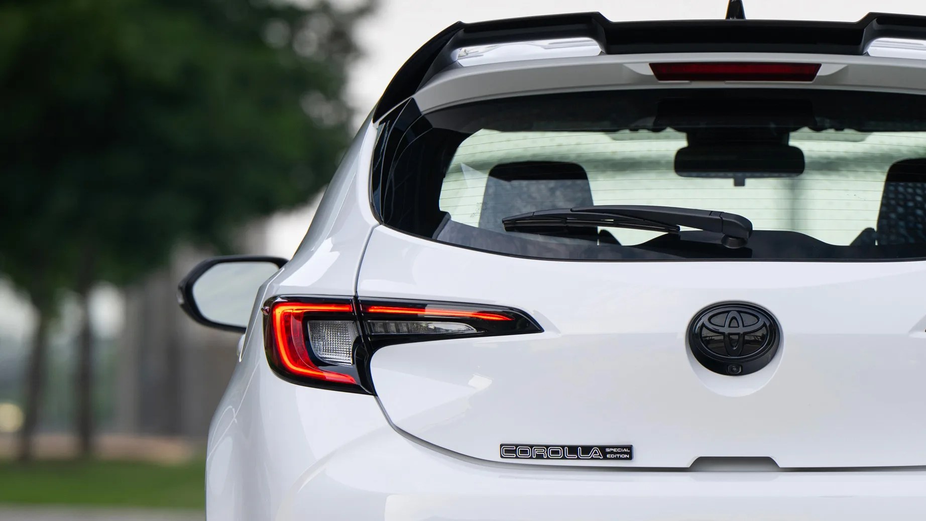 Rear view of a white Toyota Corolla Special Edition hatchback showing taillight, rear window wiper, and badge.