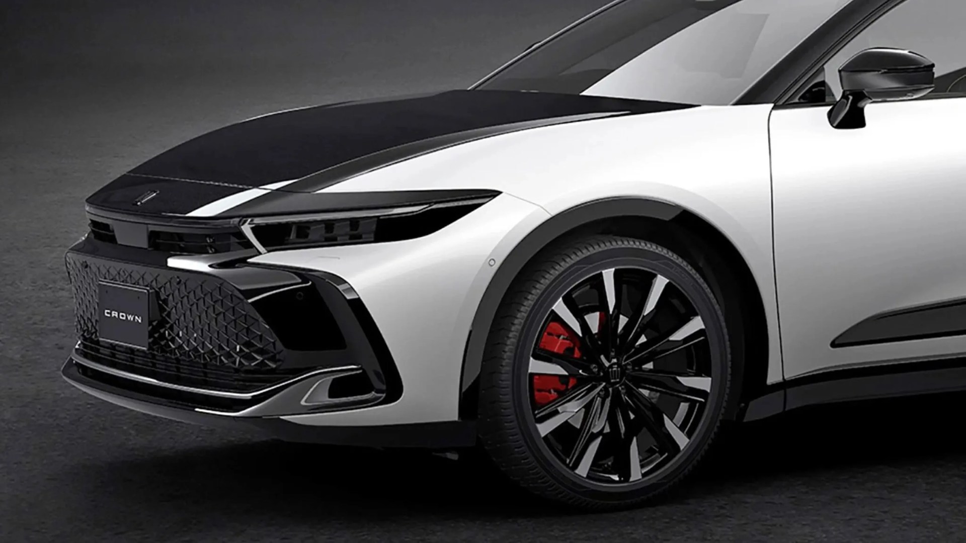 Front side of a white and black Toyota Crown with black and silver alloy wheels and red brake calipers.