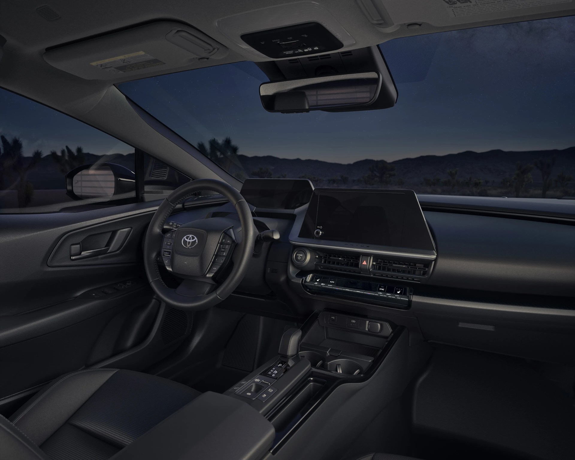 Interior of a Toyota vehicle showing a black steering wheel, digital dashboard, touchscreen display, and center console at night.