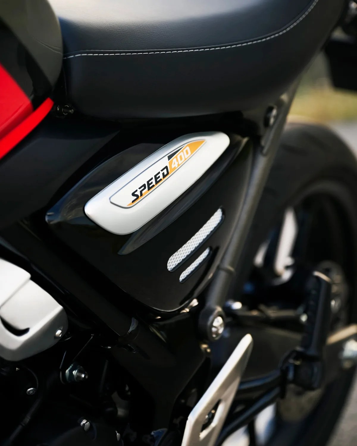 Close-up of a black motorcycle with a white and orange "Speed 400" emblem near the seat.
