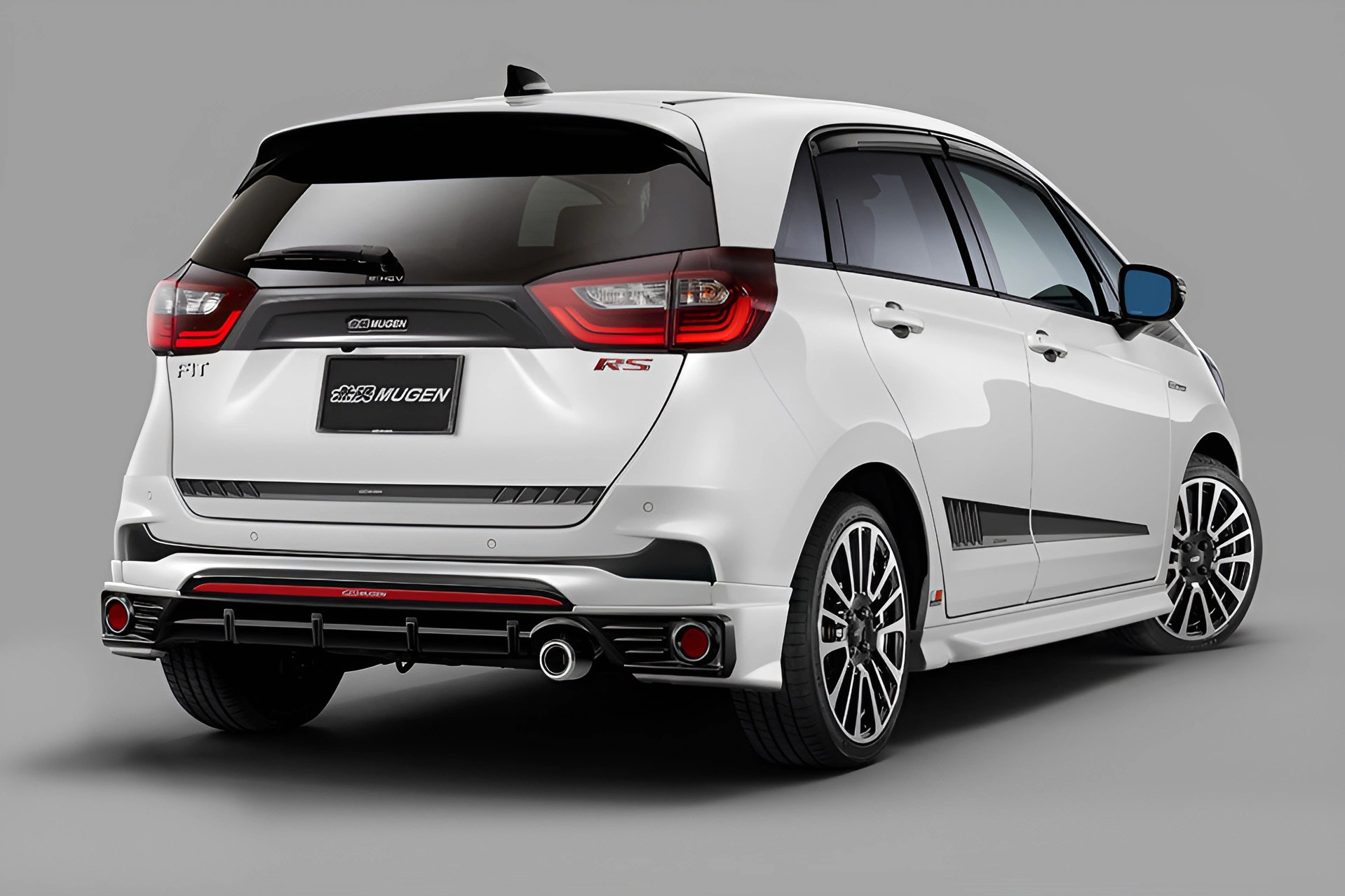 White Honda Fit RS hatchback with Mugen body kit and black tinted windows, shown from rear side angle.