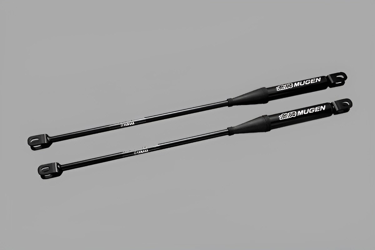Two black Mugen gas struts with mounting brackets on a gray background.