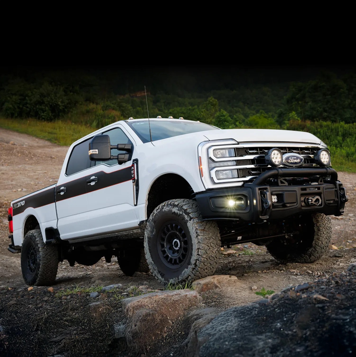 White Ford F-370 pickup truck with black accents and off-road tires on rocky terrain.