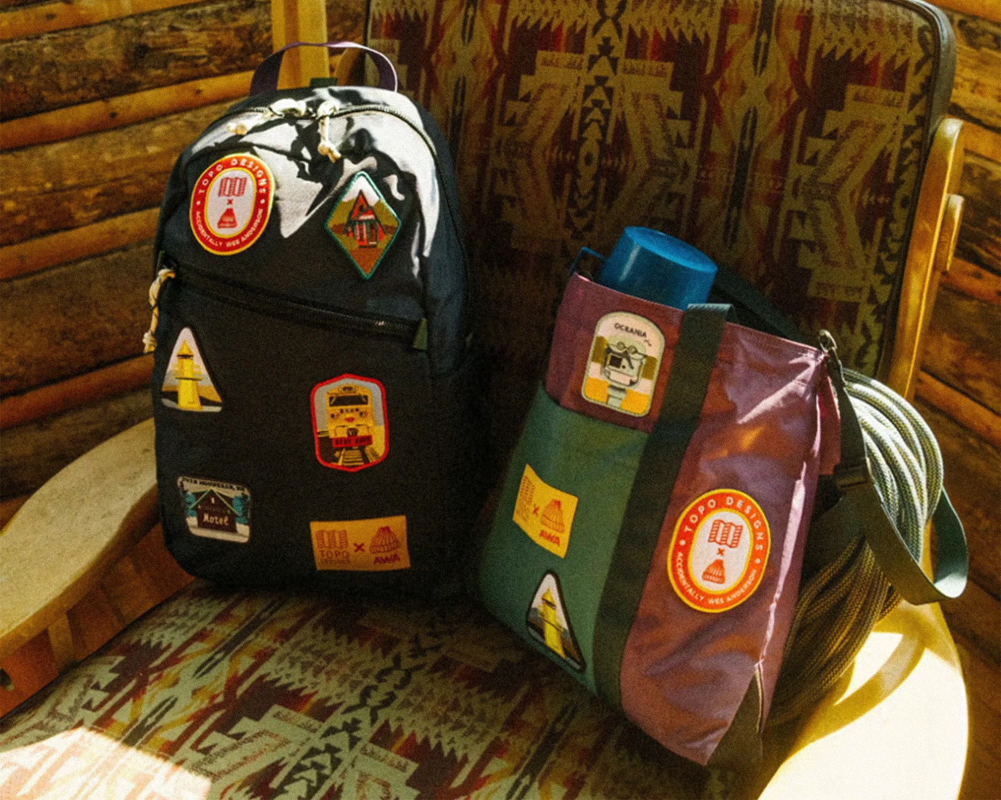 Black backpack and multicolored tote bag with various colorful patches on a patterned chair.