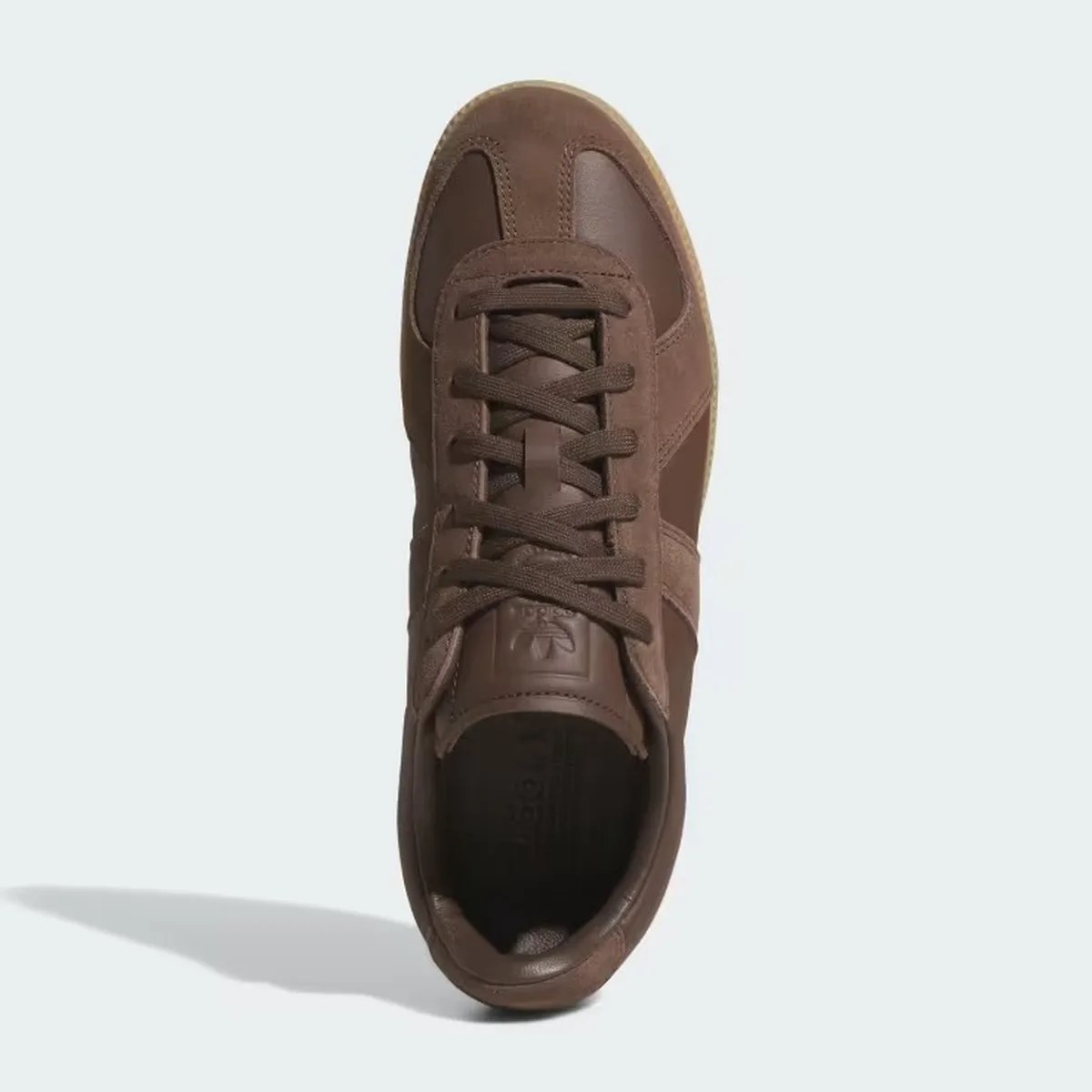 Top view of a brown leather and suede sneaker with laces on a light background.