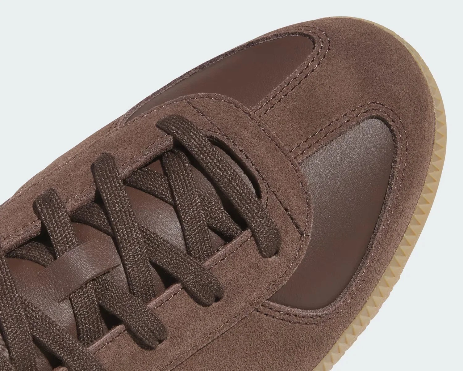 Close-up of a brown sneaker with suede and leather panels and matching brown laces.