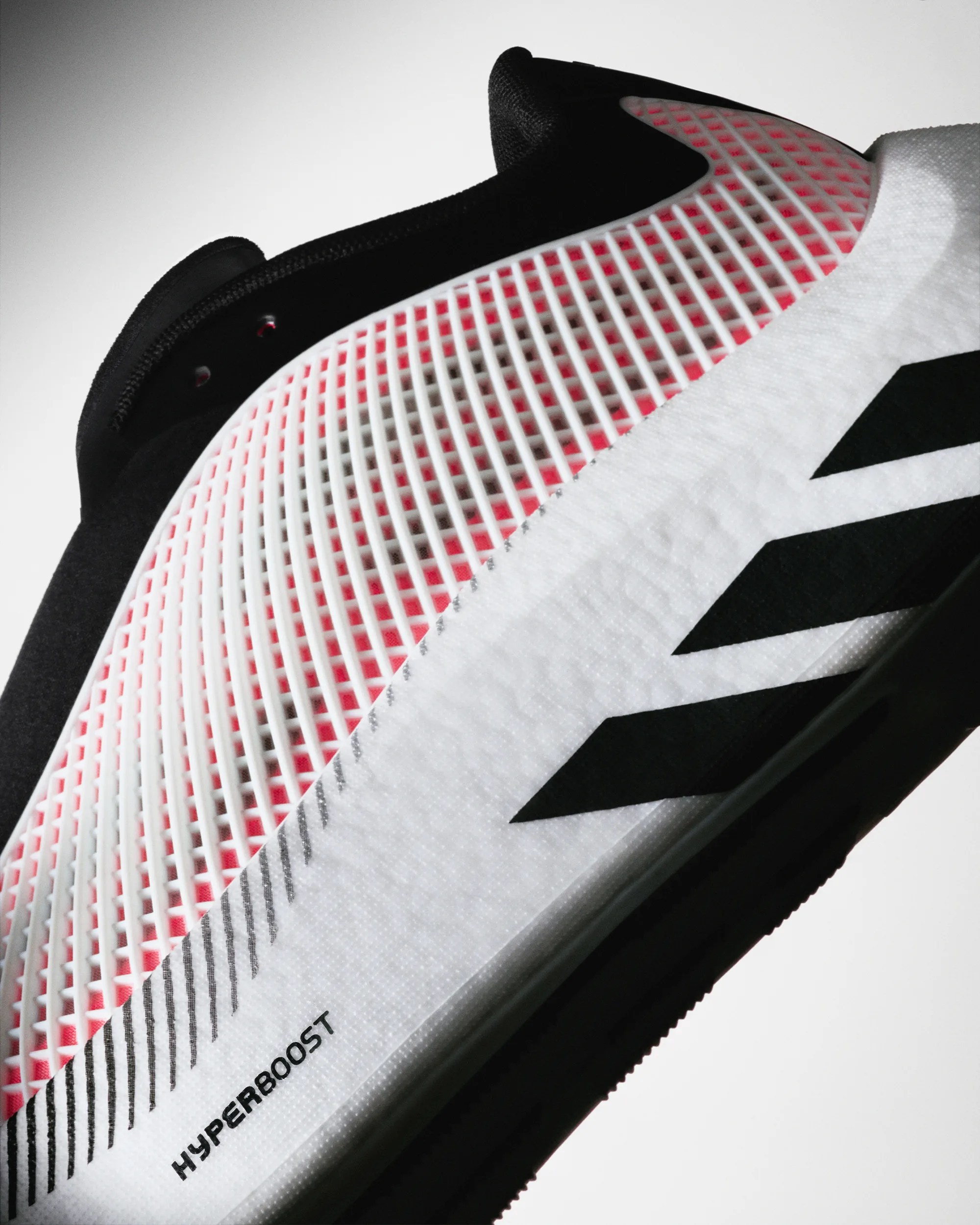 Close-up of a white and black athletic shoe with a red grid pattern and "HYPERBOOST" text on the side.