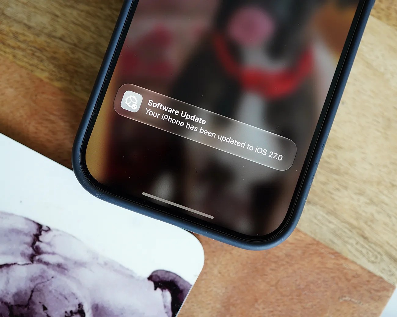 Close-up of a smartphone screen showing a notification that the iPhone has been updated to iOS 27.0.