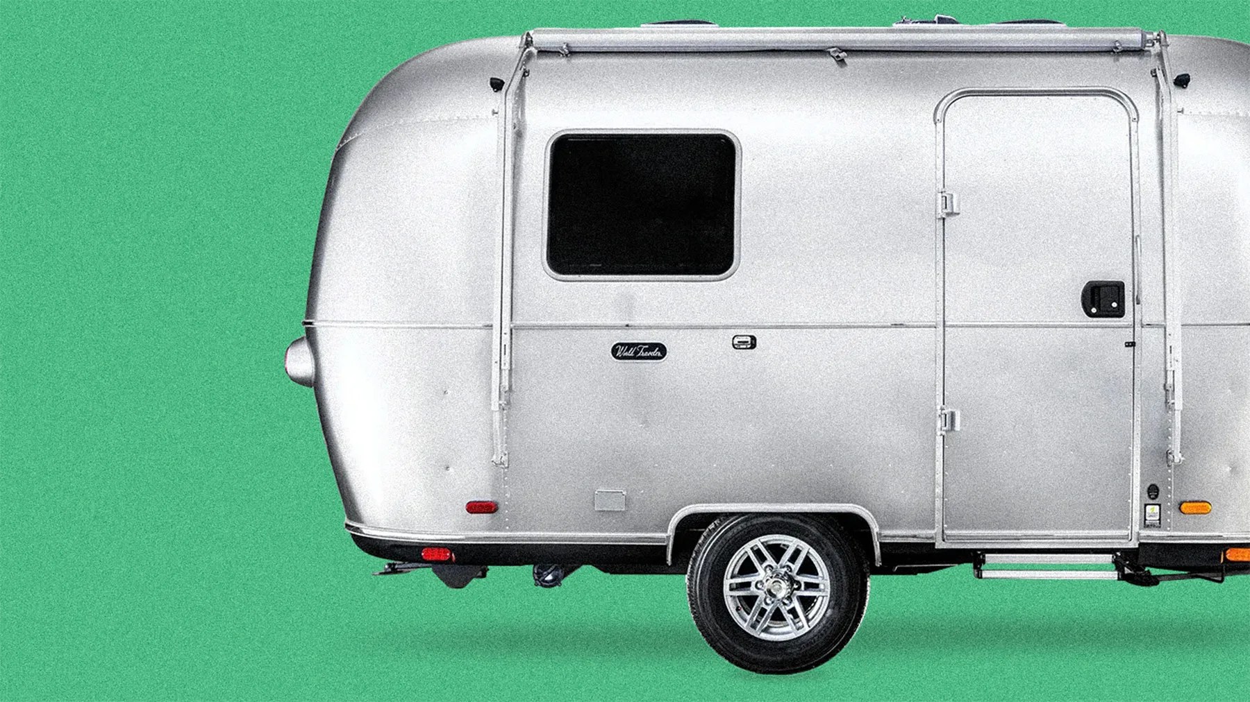 Silver travel trailer with a single axle and a side door against a green background.