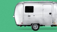 Silver travel trailer with a single axle and a side door against a green background.