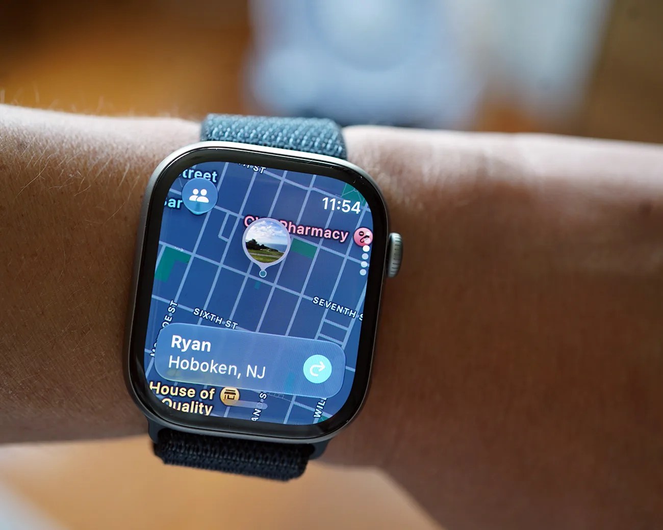 Smartwatch with a blue fabric band displaying a map and location details for Ryan in Hoboken, NJ.