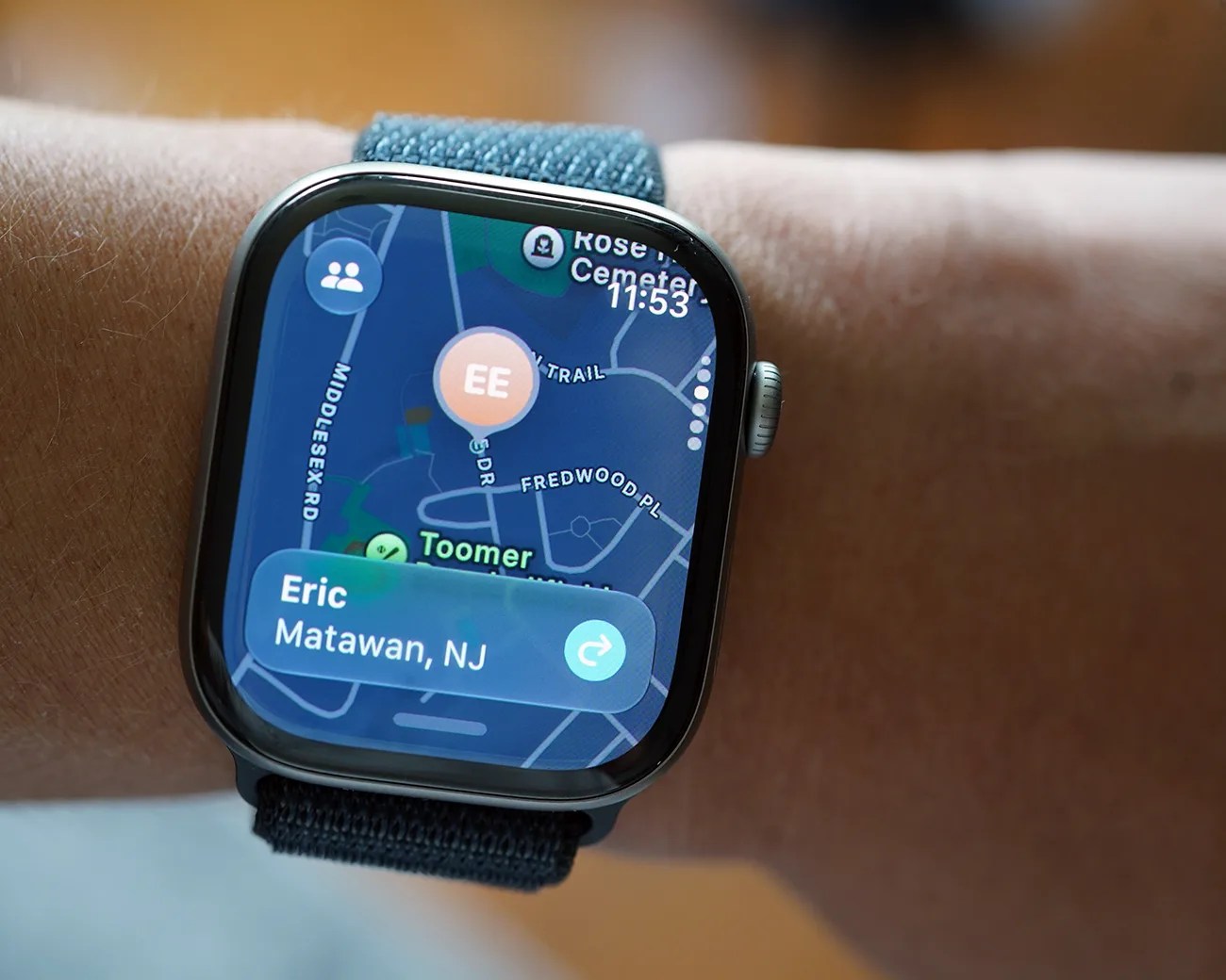Smartwatch with a blue fabric band displaying a map and location info for "Eric Matawan, NJ" on a wrist.