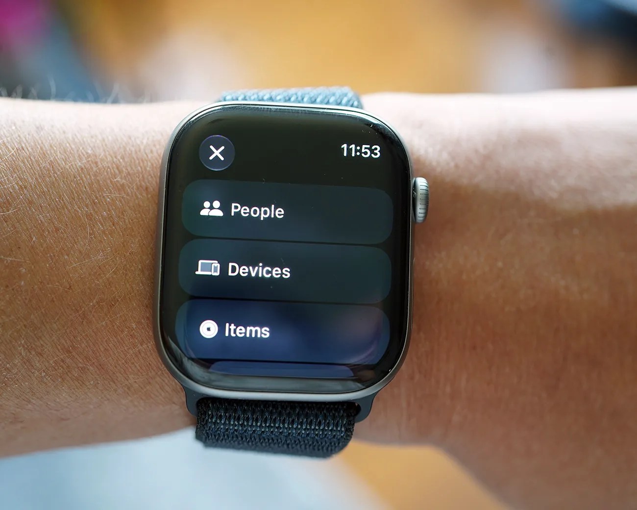 Smartwatch with black woven band displaying a menu with options for People, Devices, and Items at 11:53.