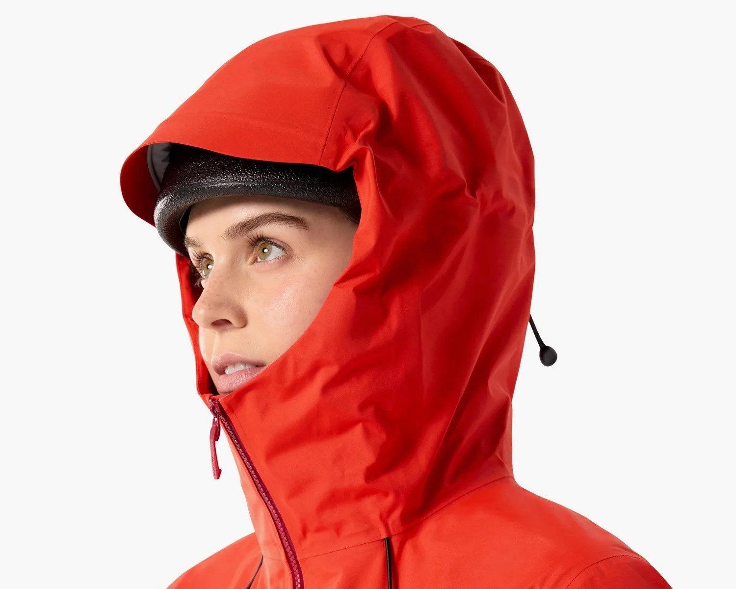Person wearing a bright red waterproof hooded jacket with a black helmet underneath.