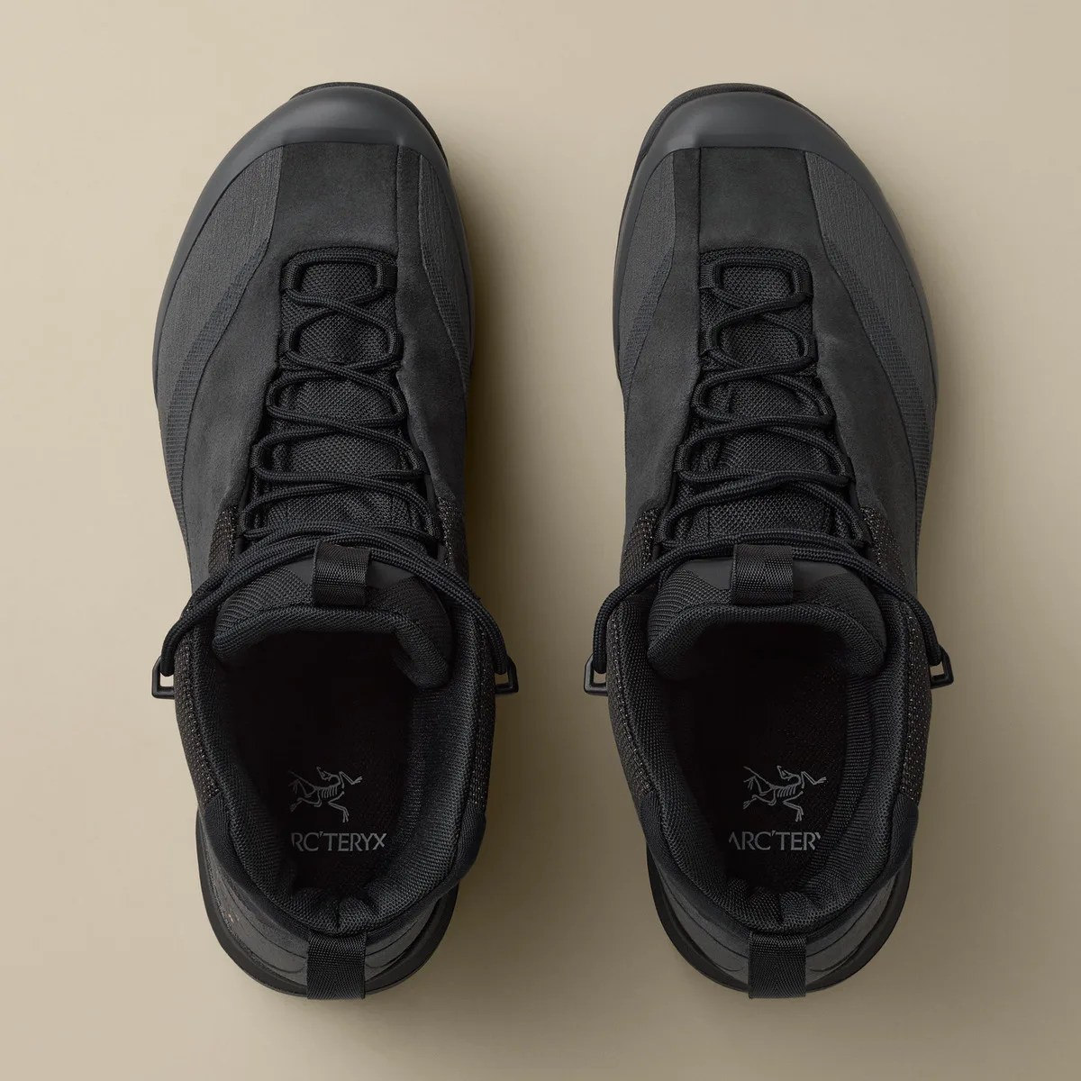Pair of black Arc'teryx hiking boots viewed from above on a beige background.