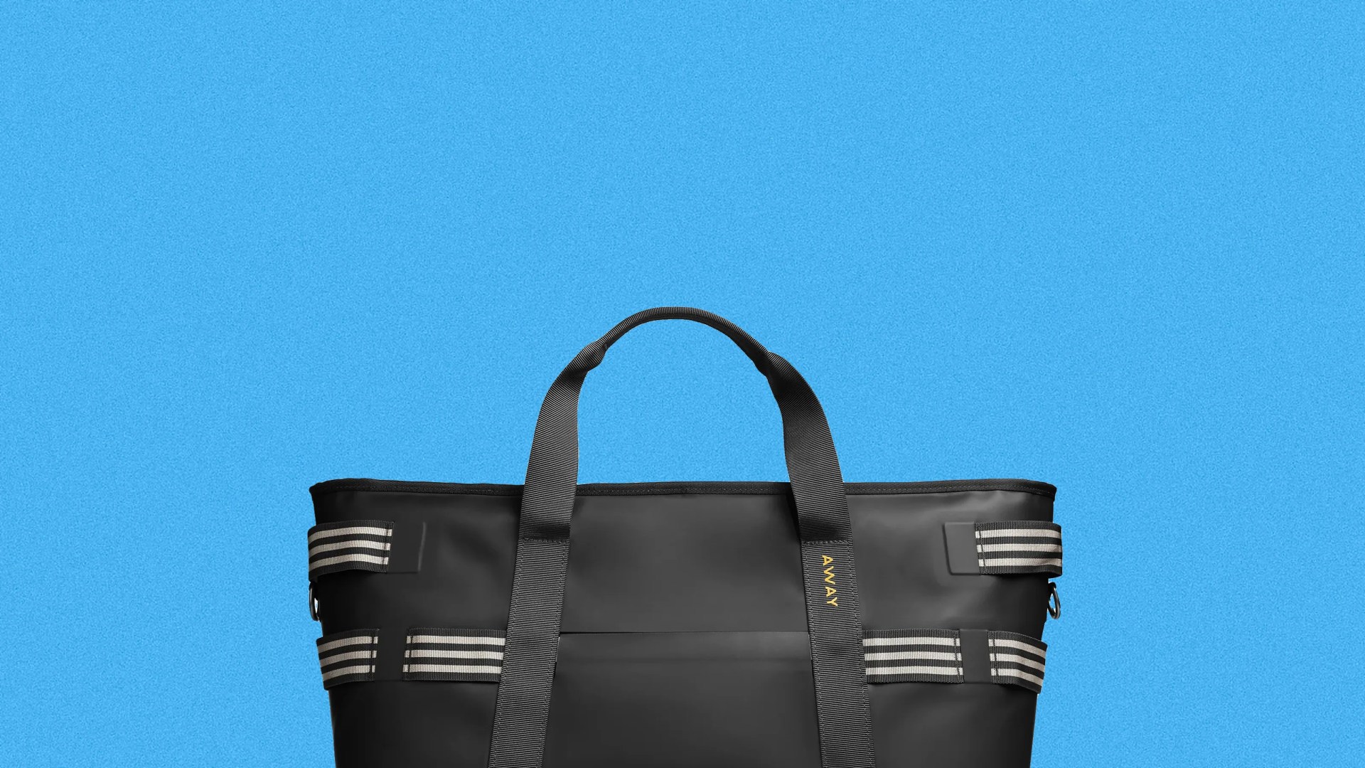 Black tote bag with striped side straps and black handles against a blue background.