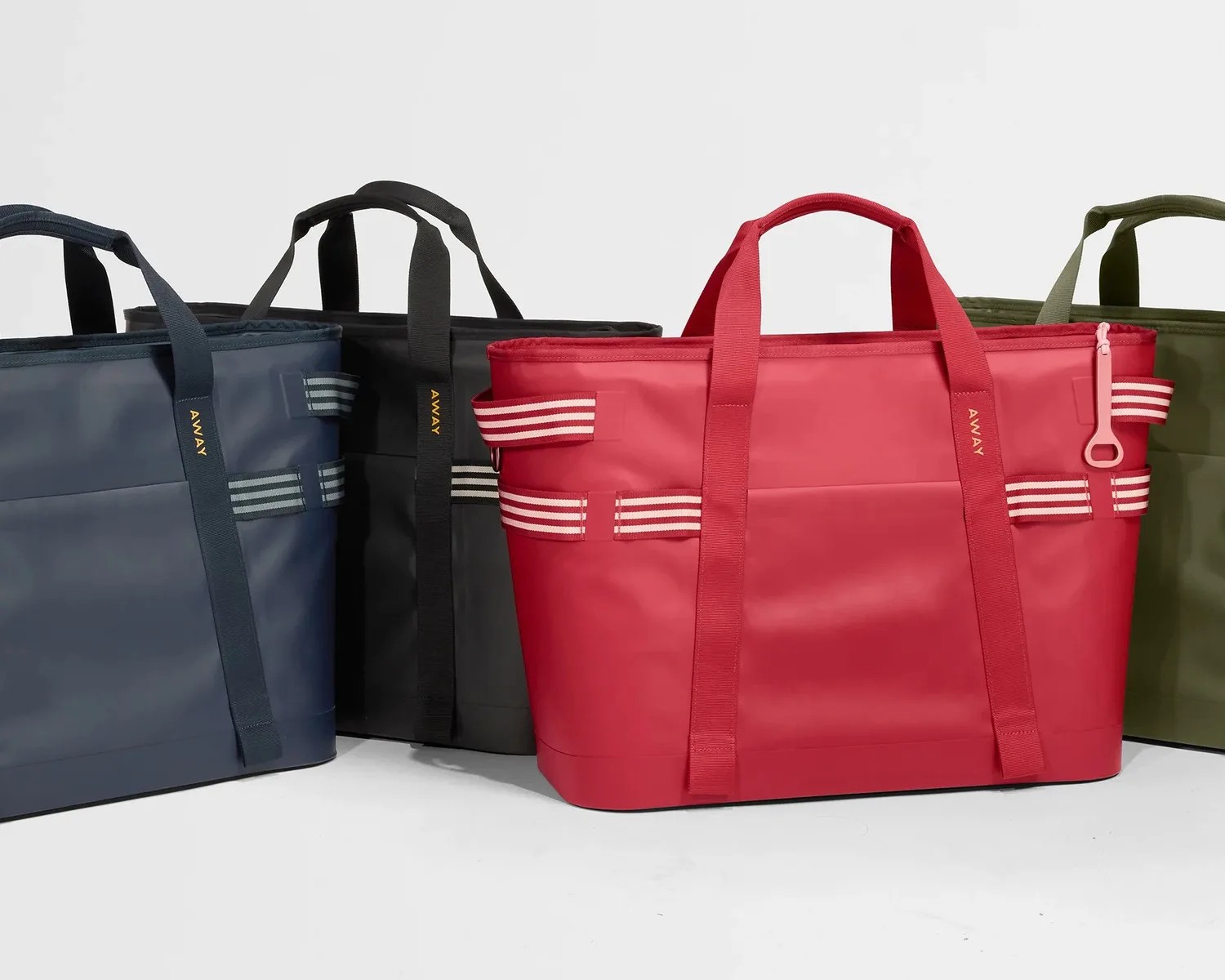 Four rectangular tote bags in navy, black, red, and olive green with striped side handles and "AWAY" printed on the straps.