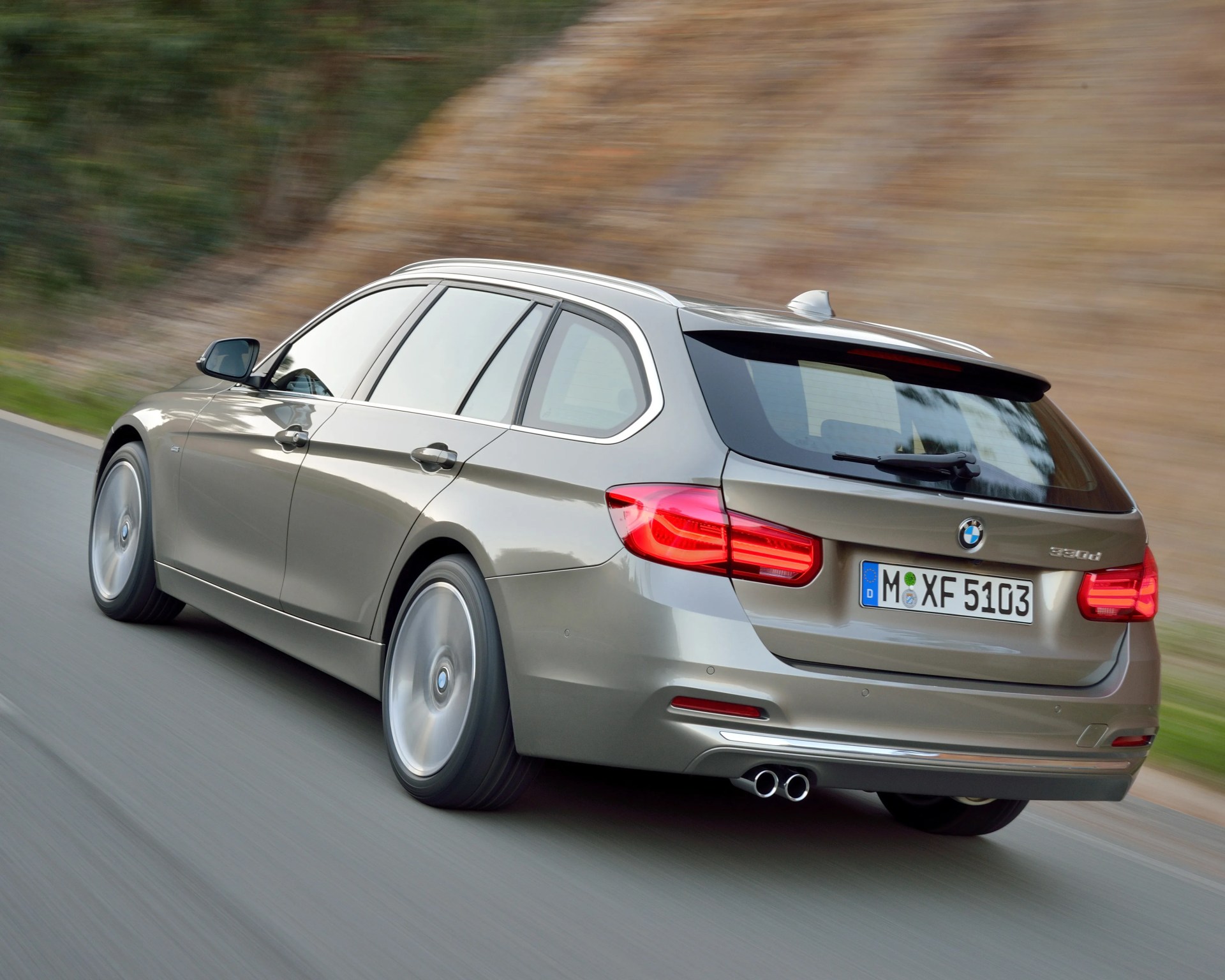 Silver BMW 330d station wagon driving on a road with blurred background.