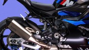 Close-up of a black and blue BMW motorcycle's rear section showing the Akrapovic exhaust, rear tire, and suspension components.