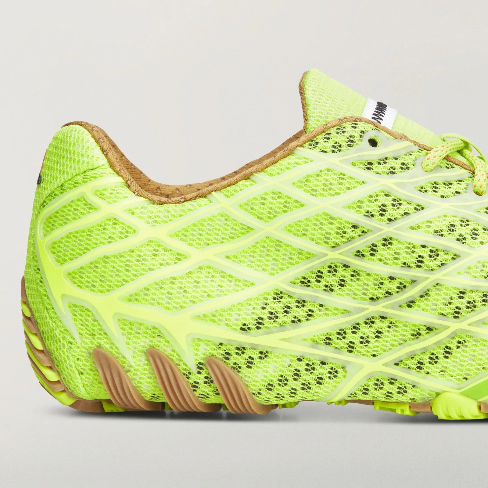 Close-up of a neon yellow mesh running shoe with brown accents and a textured sole.