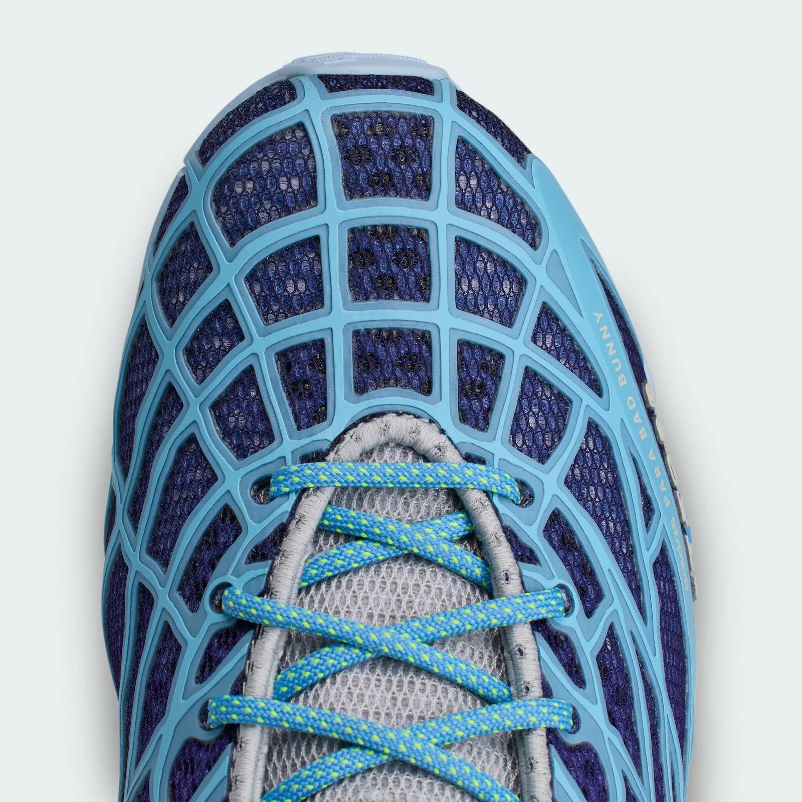 Close-up of a blue and gray mesh sneaker toe with light blue cage overlay and blue laces with yellow dots.