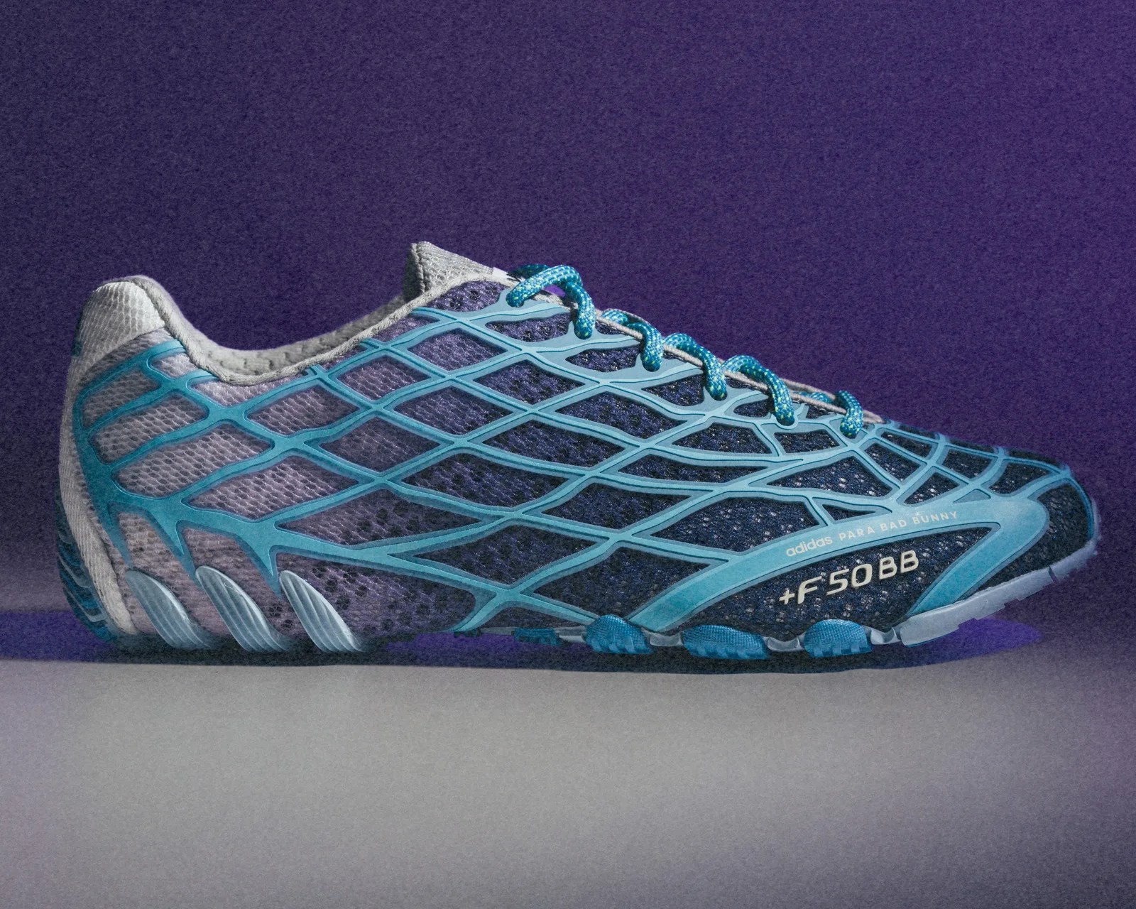 Blue and gray Adidas running shoe with a web-like overlay and "adidas PARA BAD BUNNY +F50BB" text on the side.