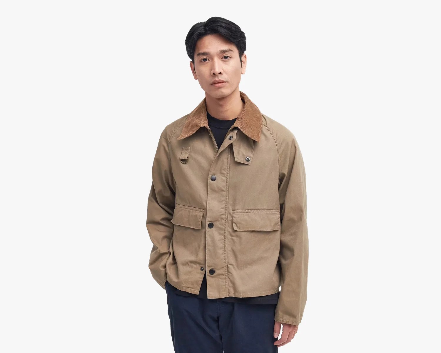 Man wearing a tan jacket with a brown corduroy collar and navy pants against a white background.