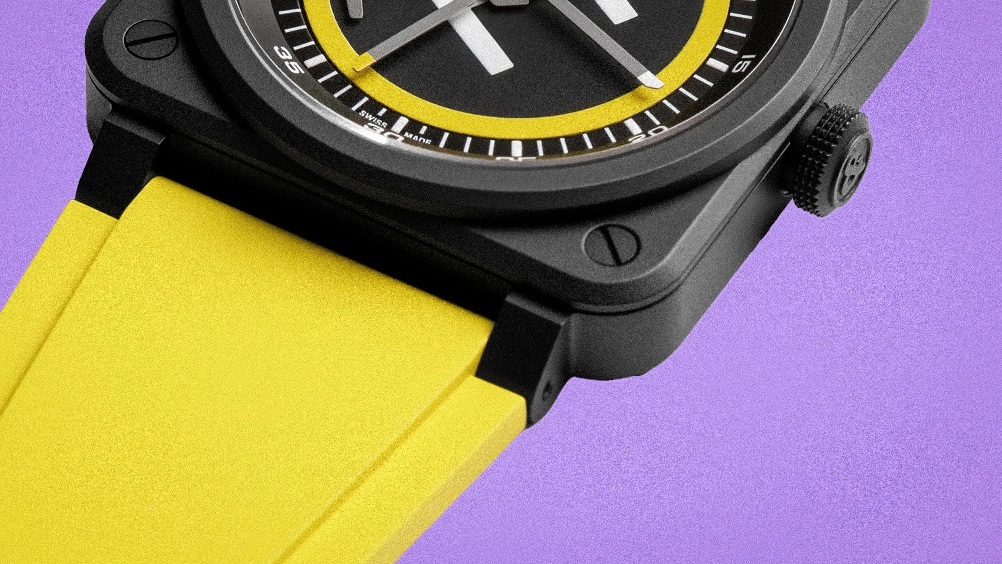 Close-up of a black square watch case with a yellow rubber strap and a black dial with yellow accents on a purple background.