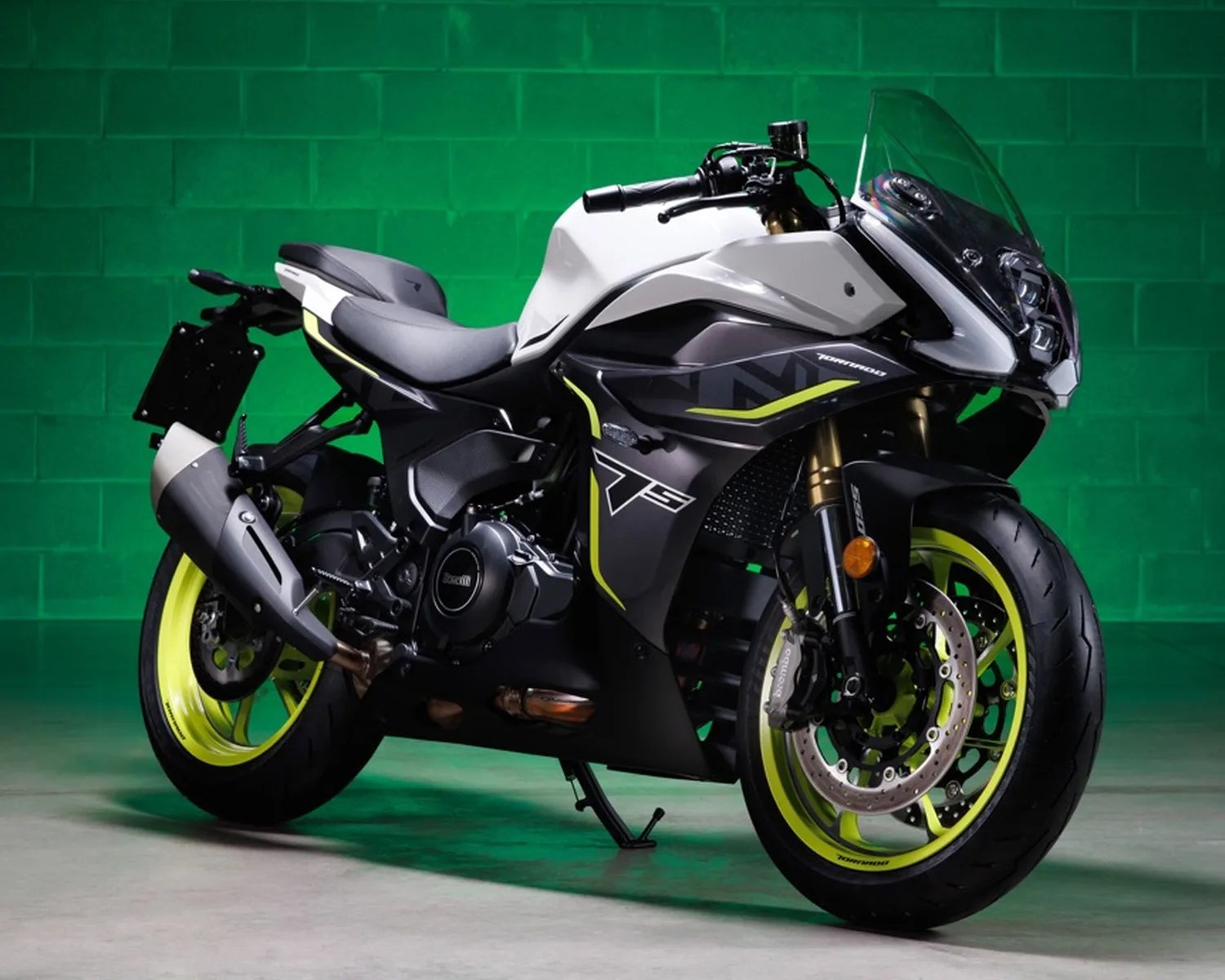 Sport motorcycle with white and black body, neon yellow wheel rims, and a clear windshield on a green background.