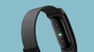 Black fitness tracker with a woven black nylon band against a blue background.
