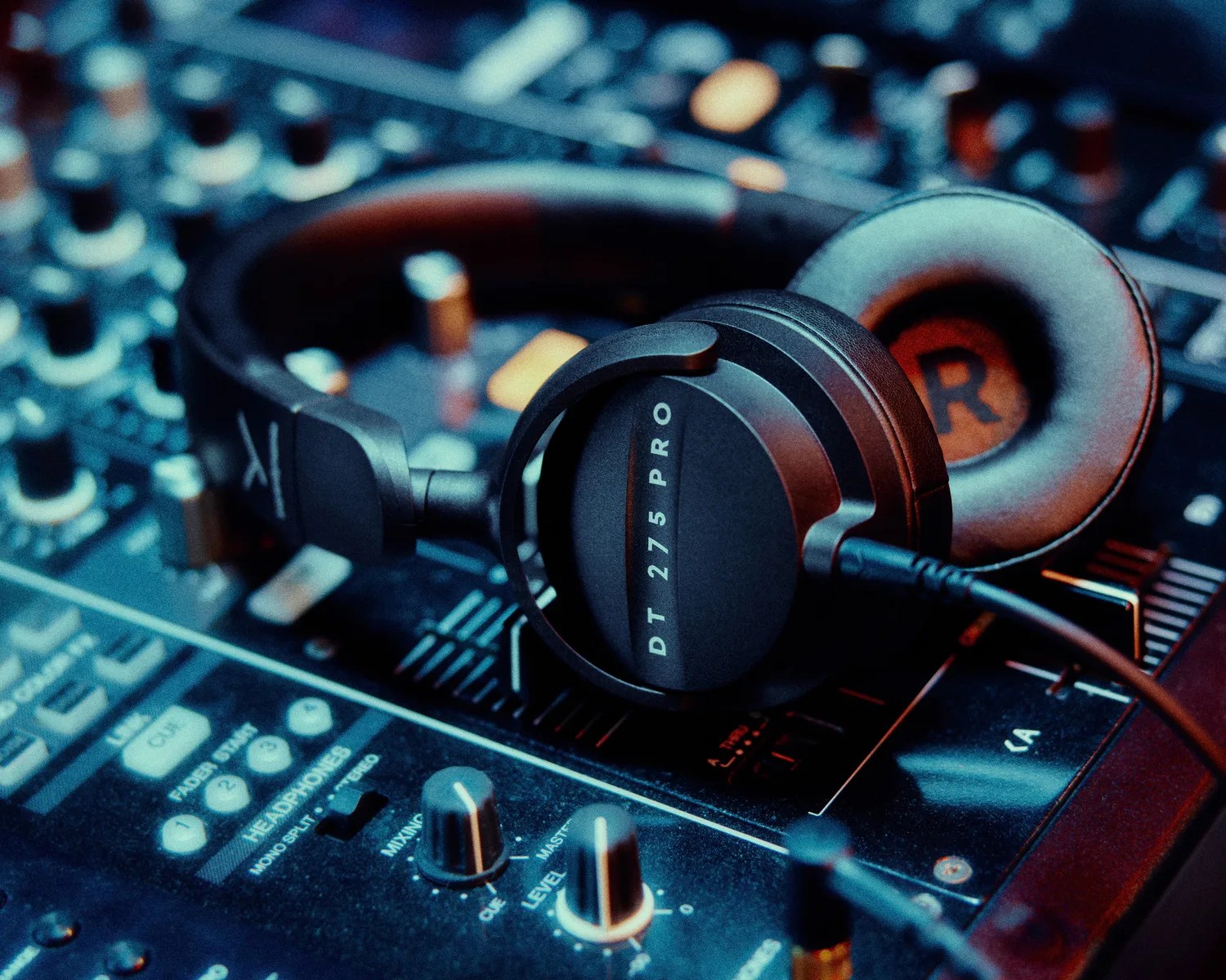 Black DT 275 PRO headphones resting on a sound mixing console with knobs and sliders.