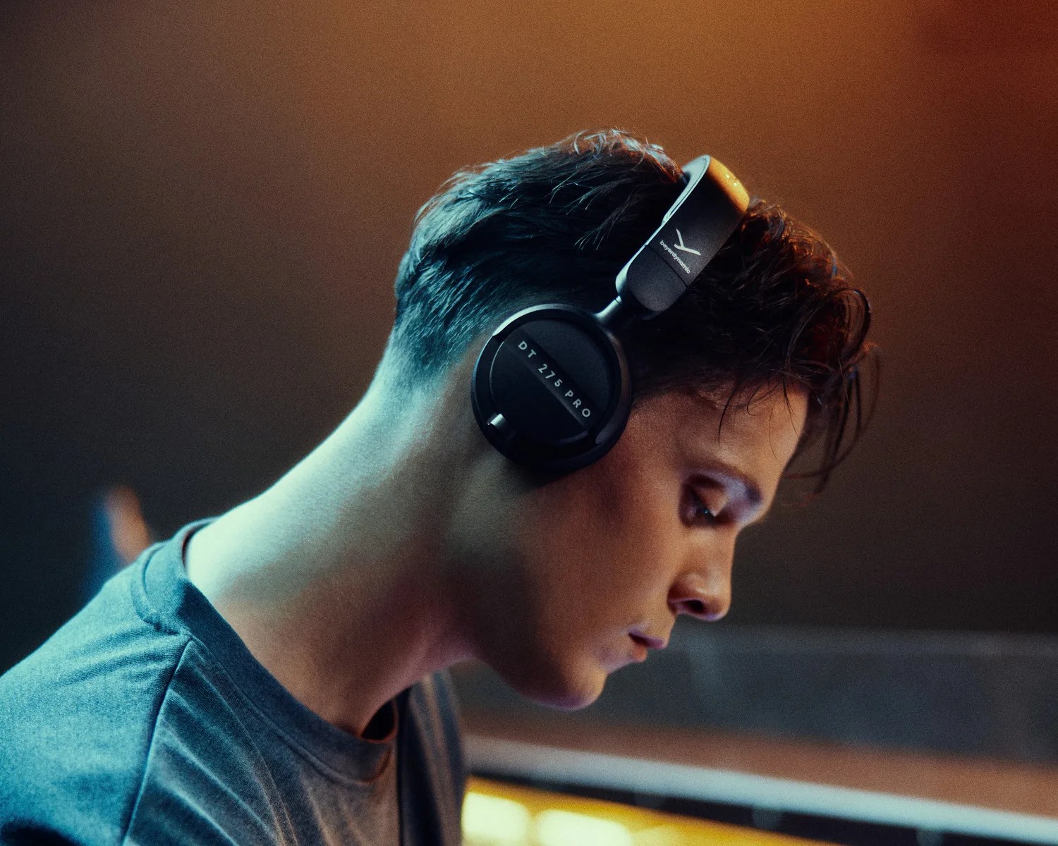 Person wearing black Beyerdynamic DT 275 Pro over-ear headphones, shown in profile.