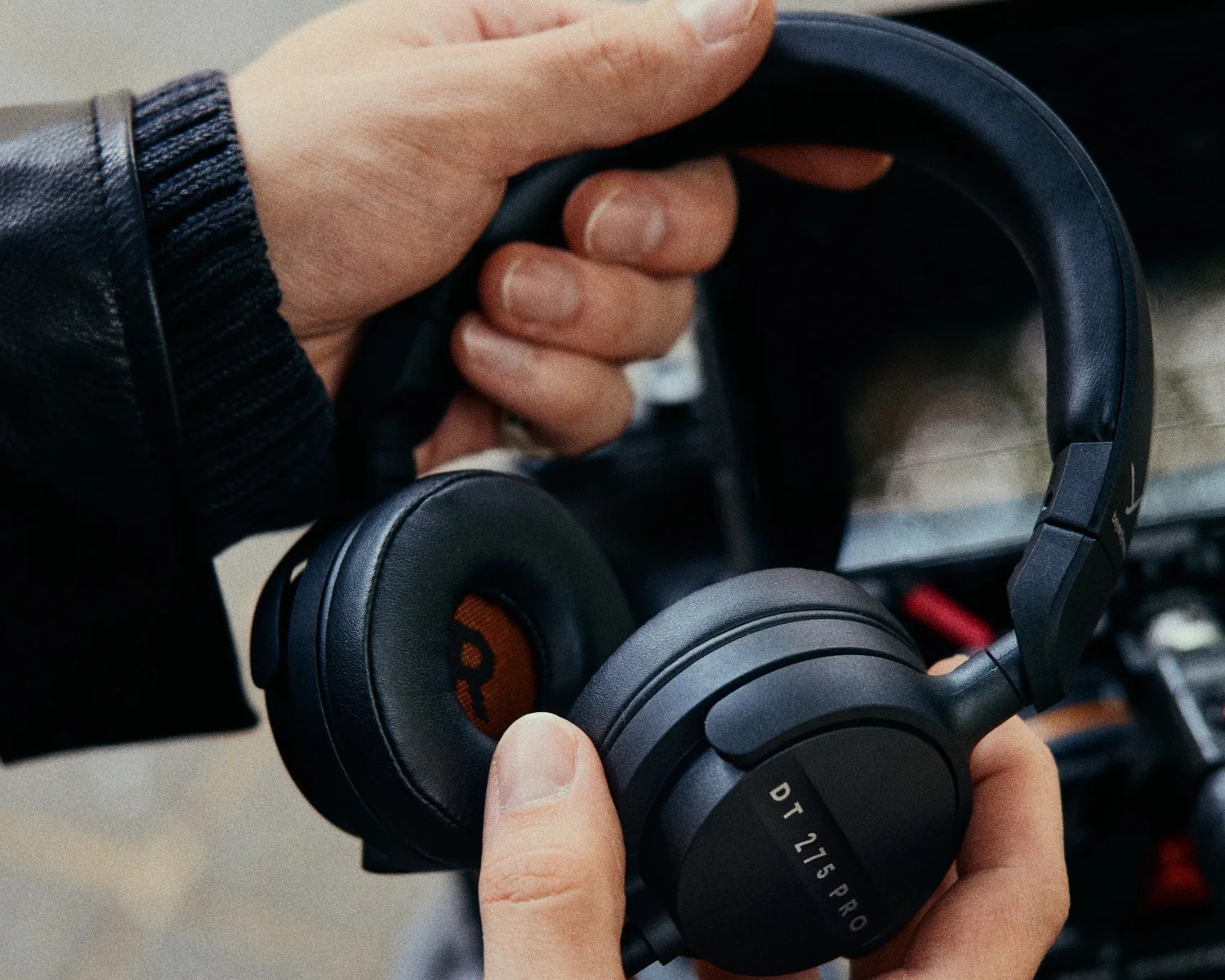 Black Beyerdynamic DT 275 PRO over-ear headphones held in hands with padded ear cups.