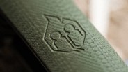 Close-up of a textured green surface with an embossed logo featuring two stylized keyhole shapes.