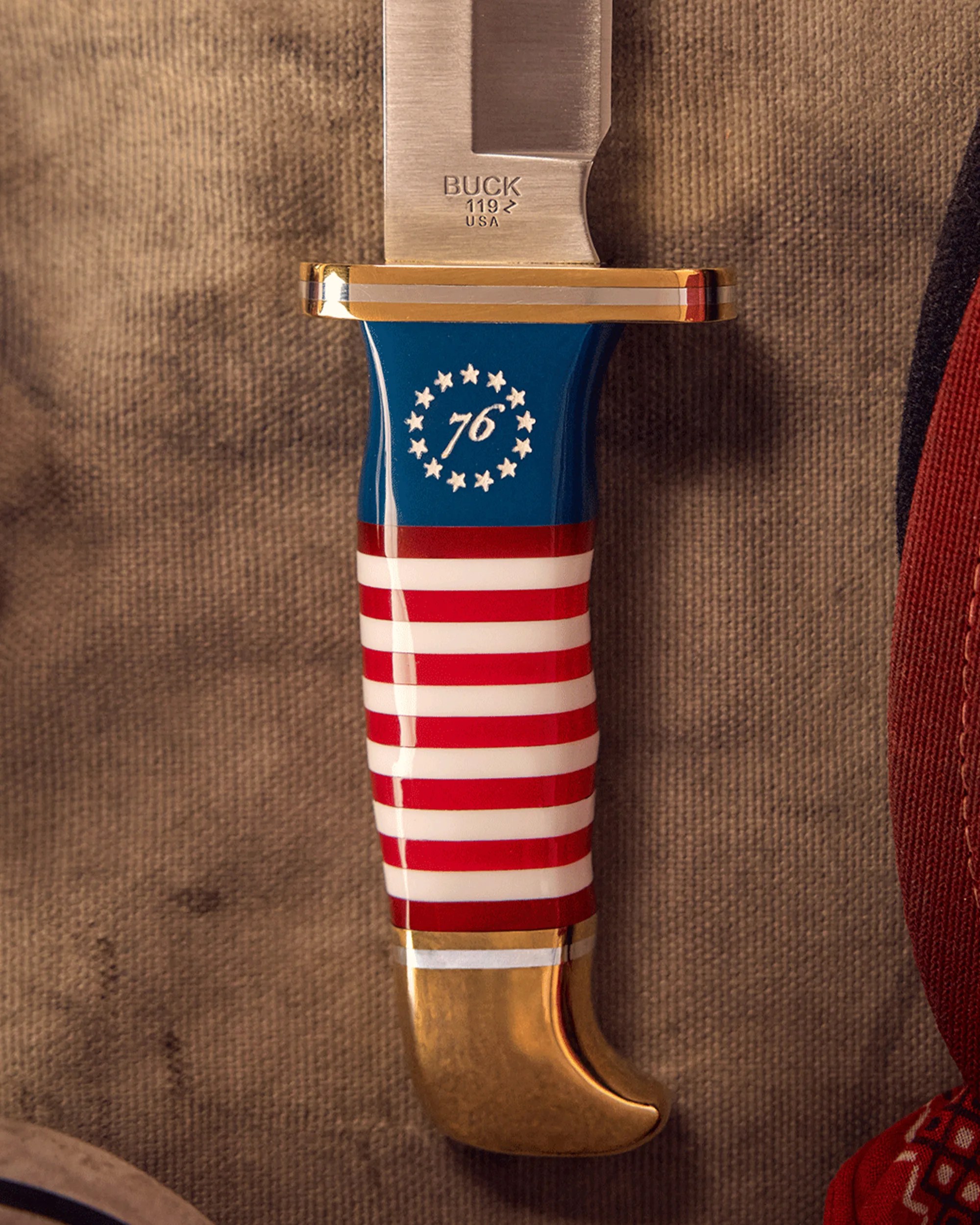 Knife handle with American flag design featuring red and white stripes, blue top with white stars and the number 76, and a brass pommel.