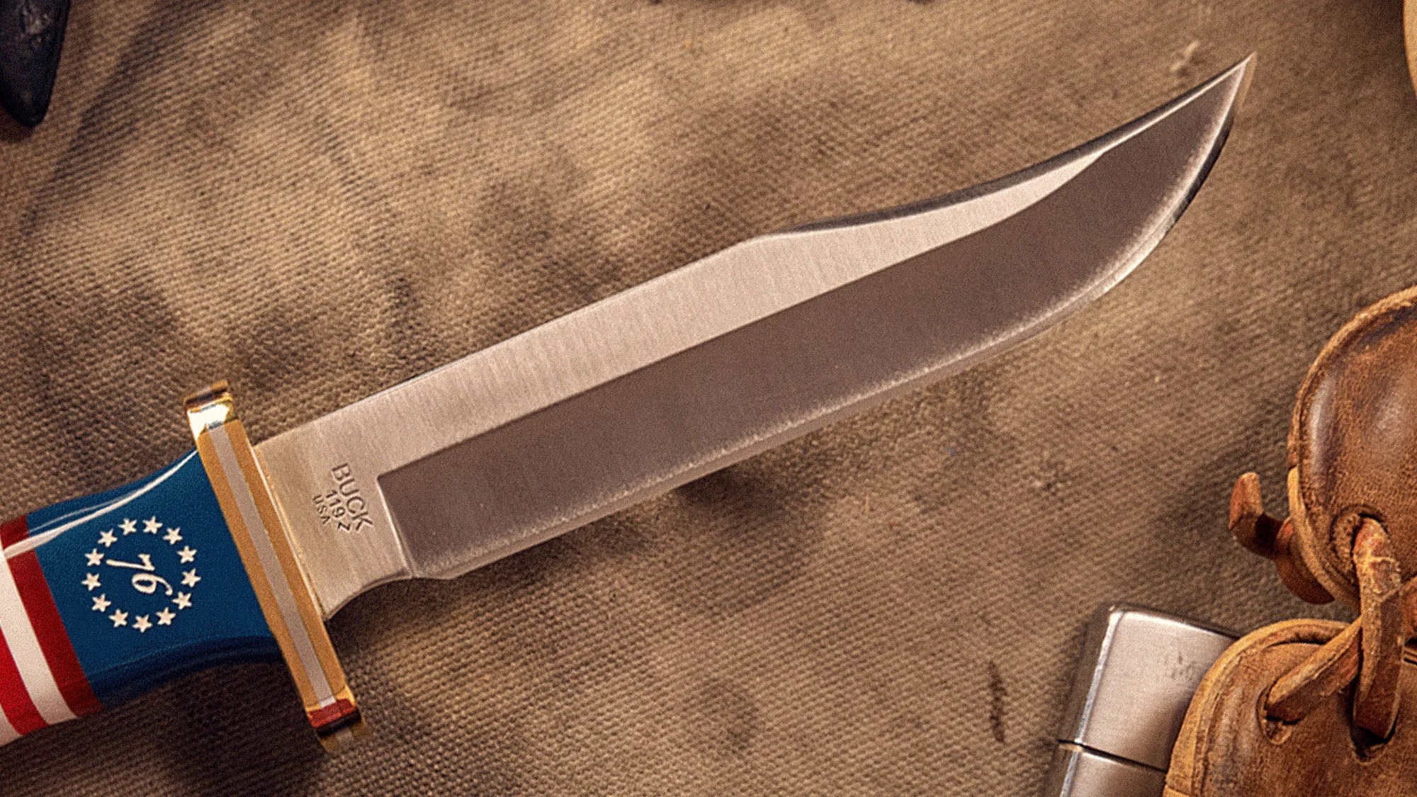 Knife blade with "BUCK 119 U.S.A." engraving and a handle featuring a red, white, and blue design with stars and stripes.