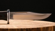 Close-up of a Buck USA fixed blade knife with a polished steel blade resting on a wooden surface.