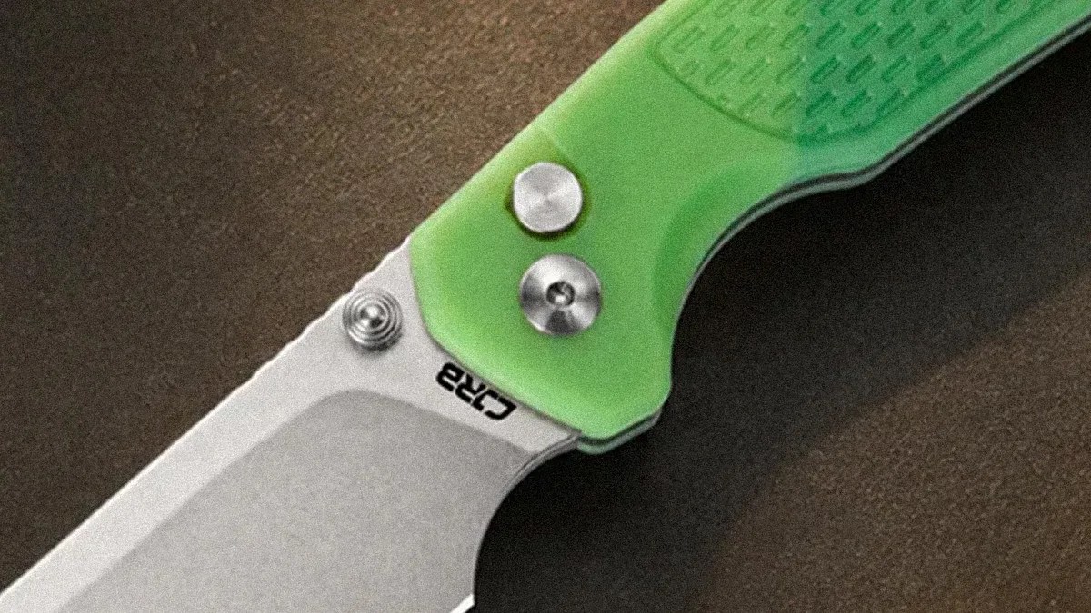 Close-up of a folding knife with a silver blade and a translucent green handle showing two metal screws.