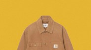 Brown Carhartt jacket with corduroy collar and front pockets on a yellow background.